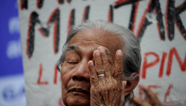 A Filipina “comfort woman” wipes away a tear during a January protest in Manila. Over 1,000 women and girls were captured and imprisoned in “rape camps” in the Philippines by the Japanese military during World War II.