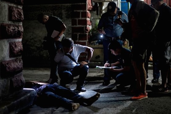 EDITORS NOTE: Graphic content / In this picture taken on July 8, 2016, police officers investigate the dead body of an alleged drug dealer, his face covered with packing tape and a placard reading "I'm a pusher", on a street in Manila. Philippine President Rodrigo Duterte on July 1 urged communist rebels to start killing drug traffickers, adding another layer to a controversial war on crime in which he has warned thousands will die. / AFP PHOTO / NOEL CELIS