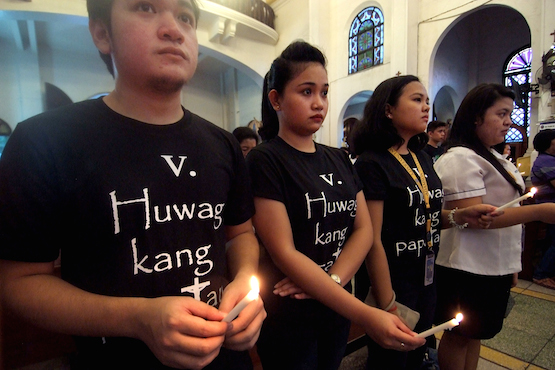 Filipino Catholics wear black shirts printed with 'Thou Shall not Kill' during a candle-lighting ceremony in Manila. (Photo by Angie de Silva)