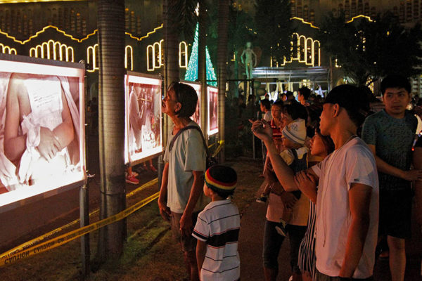 Churchgoers view photos of alleged extrajudicial killings displayed outside the Baclaran Church. (Photo by Vincent Go)