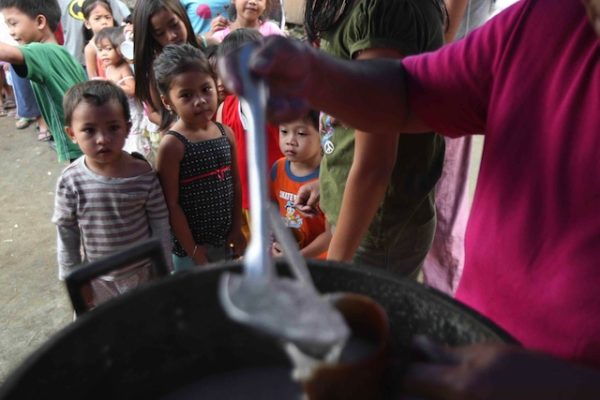 SATIATING HUNGER. Children wait their turn at a feeding program for informal settlers in Quezon City. File photo by Rolex dela Peña/ EPA