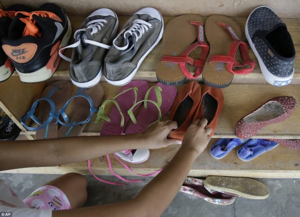 This image shows a former cybersex victim arranging a shoe rack at a shelter for sexual exploitation survivors in Manila, Philippines