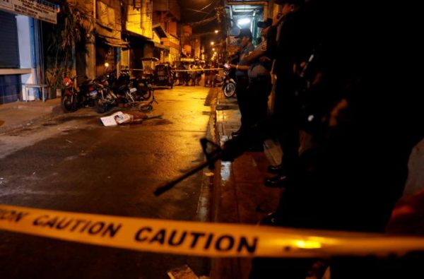 Policemen stand guard near the body of a man killed during what police said was a drug related vigilante killing in Pasig, Metro Manila, February 2017. REUTERS/Erik De Castro