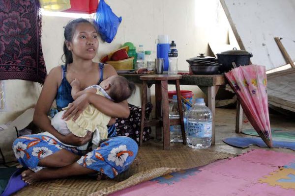 A mother and child displaced by super typhoon Haiyan in 2013 await help in a temporary shelter in the province of Cebu. (Photo by Joe Torres)