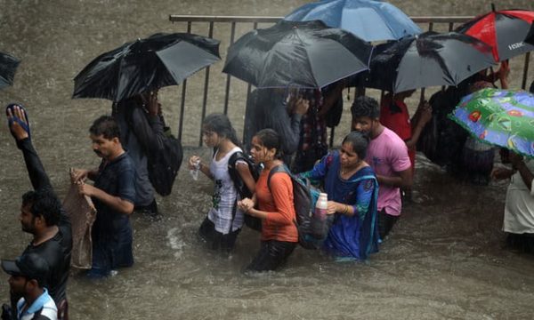 People walk along a flooded street in Mumbai. Photograph: Punit Paranjpe/AFP/Getty Images